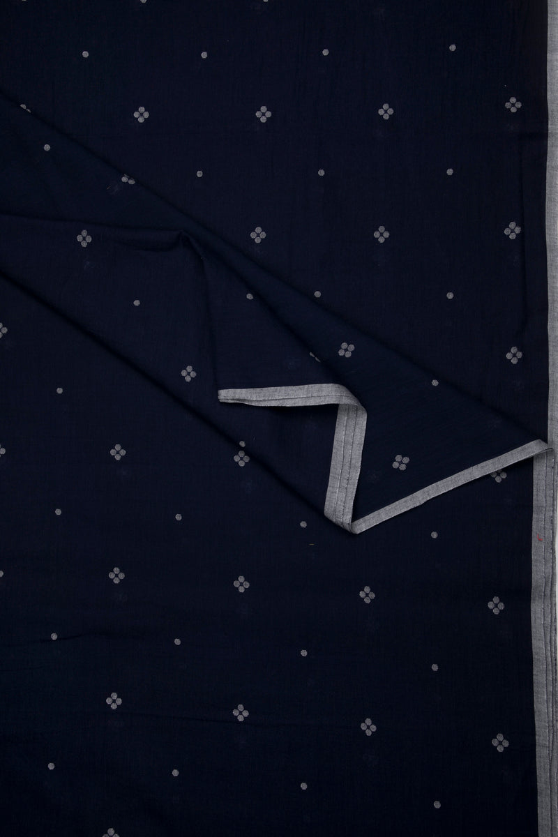Artisan-made dark indigo Jamdani cotton fabric with delicate floral weaving and grey selvedge edge, sustainable textile from Bengal