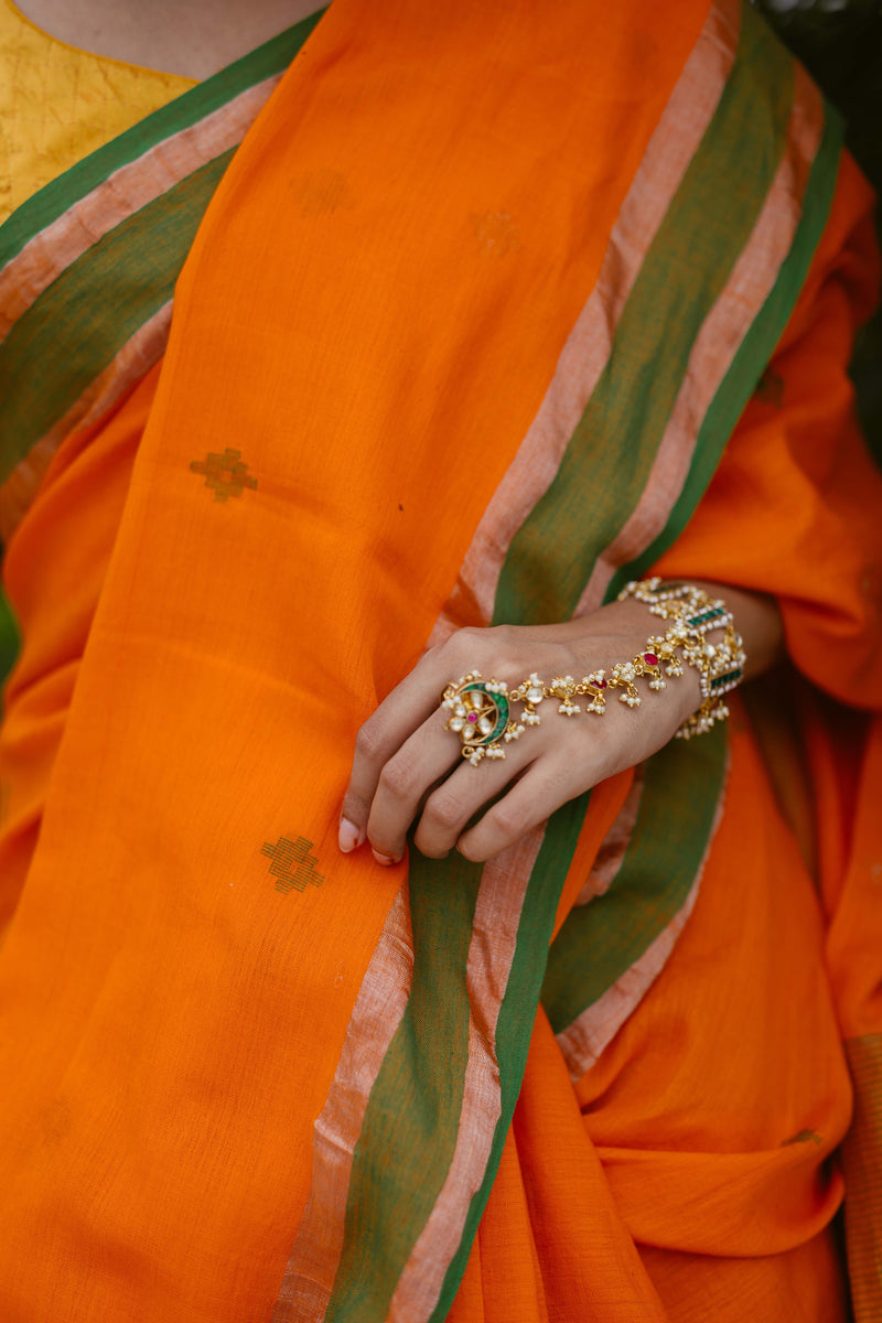Close-up of zari jamdani motifs on orange handloom cotton saree.