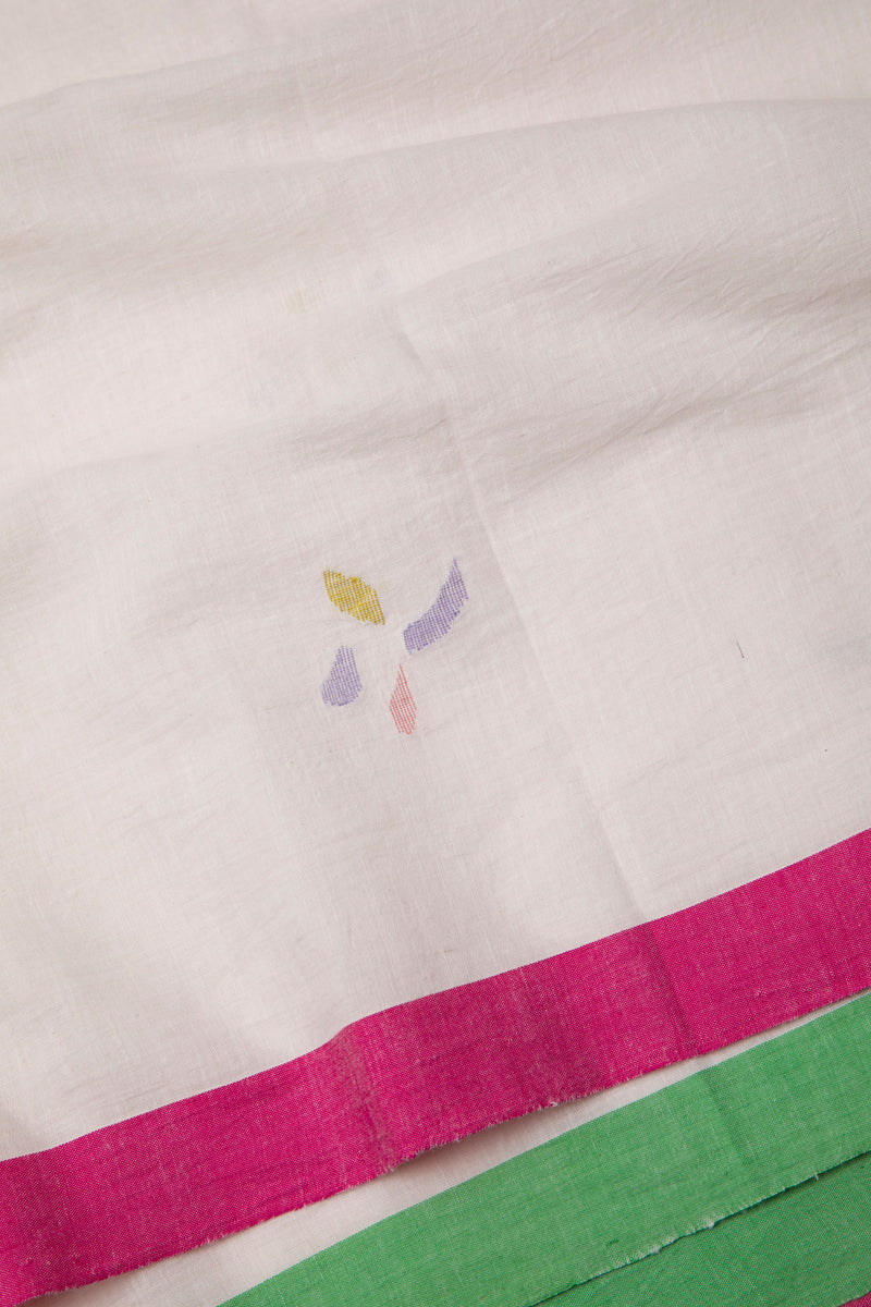 Close-up of a fabric with colorful jamdani and pink and green borders on a off-white background