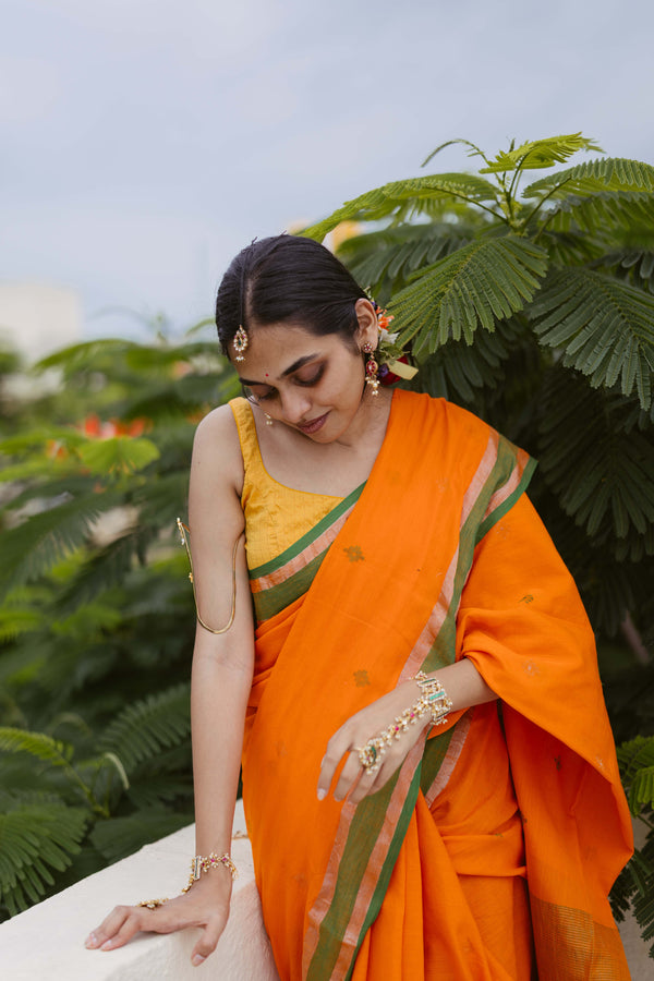 Model wearing Orange handloom cotton Jamdani saree with bottle green border and zari motifs