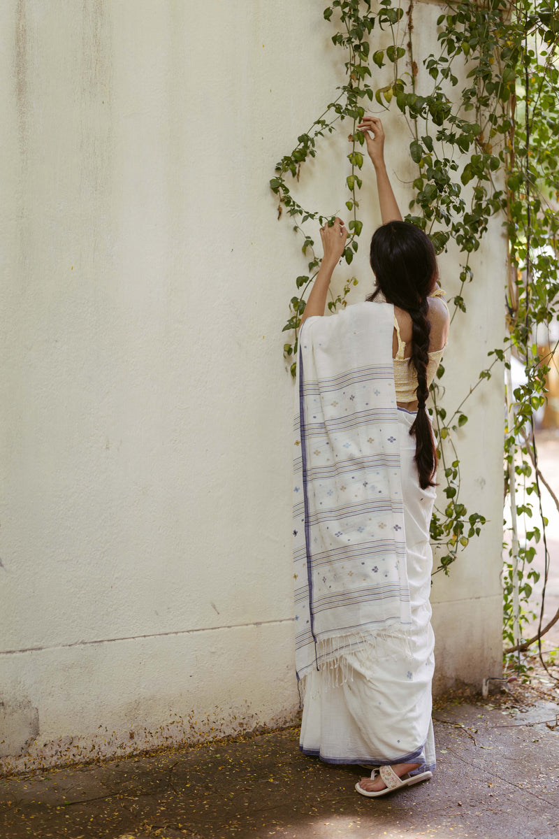 Woman in a white saree with blue jamdani floral motifs 