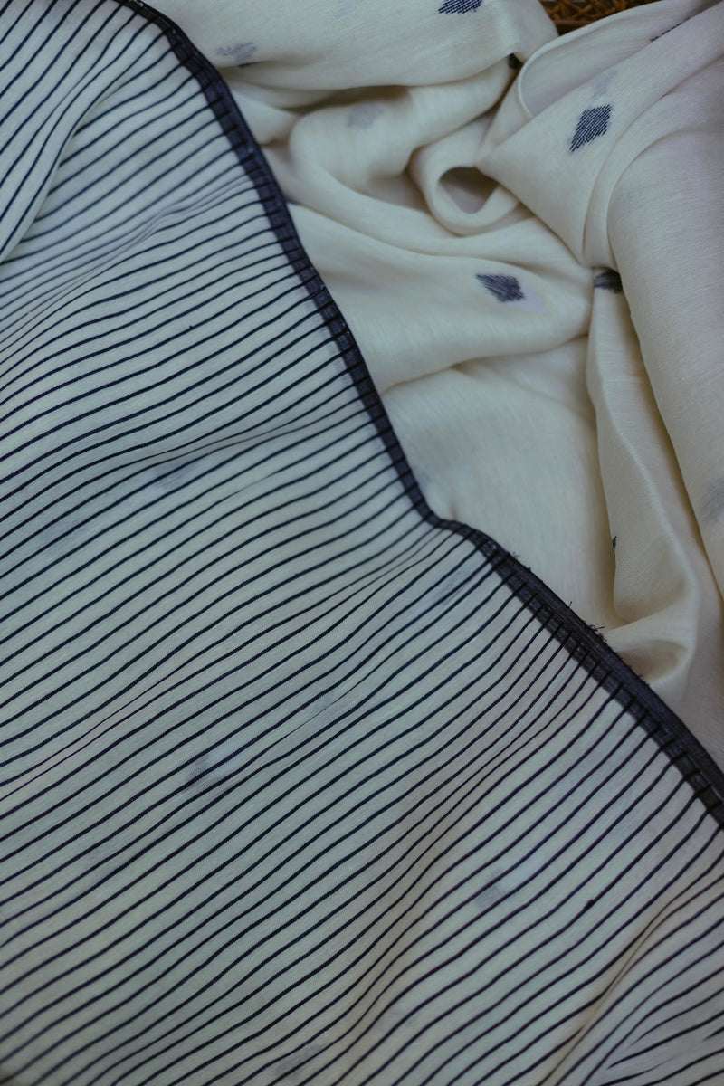 Handwoven White & Indigo linen Jamdani saree displayed in natural light with intricate weave.