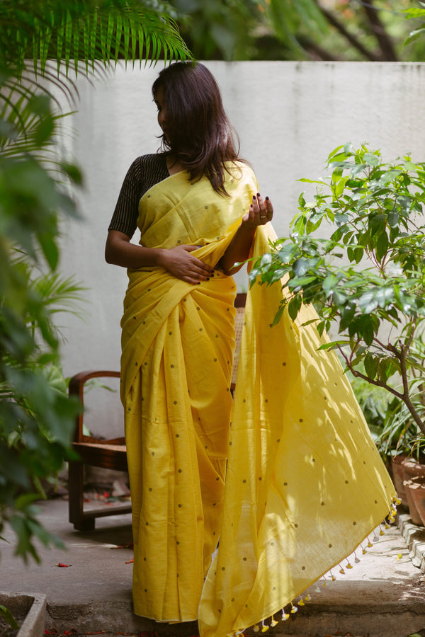 Vibrant yellow handwoven Khadi Jamdani saree in garden setting, authentic Indian ethnic attire