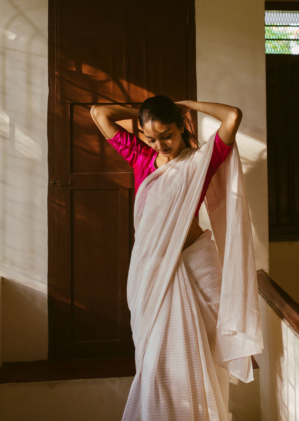 Elegant handwoven muslin saree with golden stripes and a pink blouse