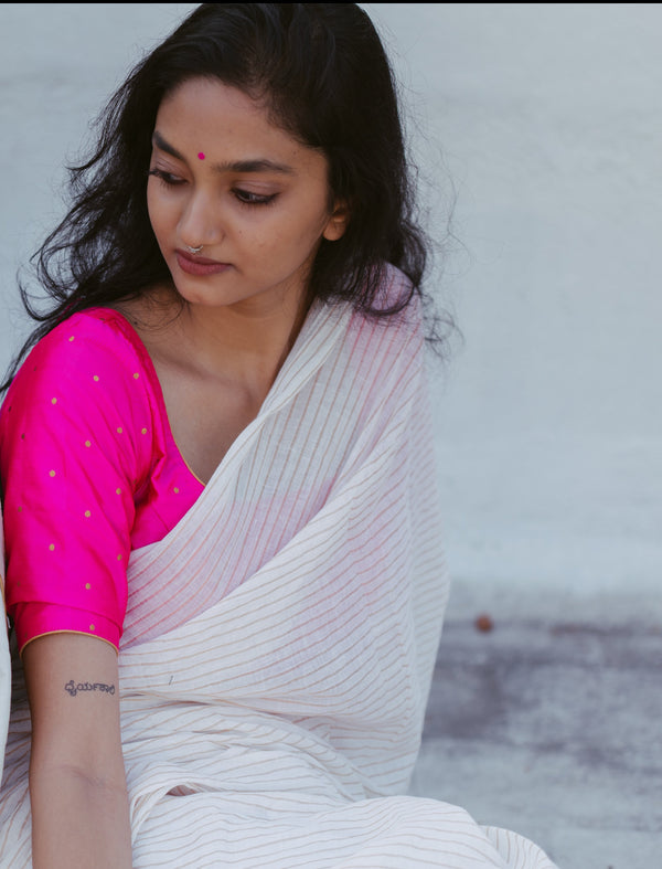 Indian woman wearing a golden striped handwoven muslin saree with a traditional pink blouse