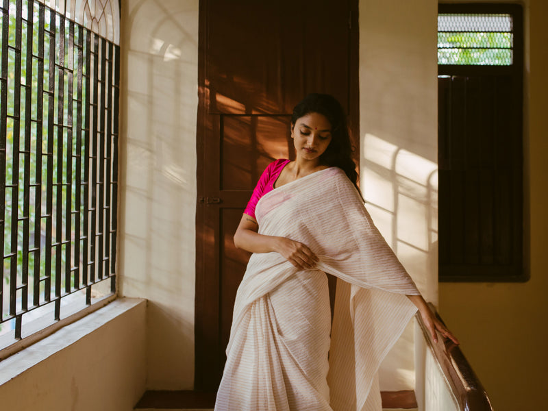 Golden stripes muslin saree styled with a vibrant pink blouse, showcasing fine handwoven details