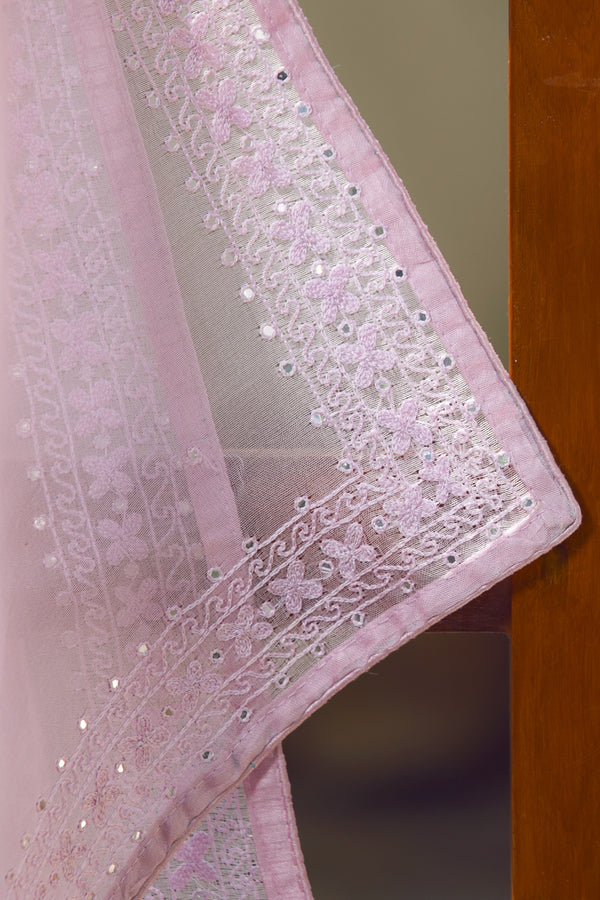 A pink organza silk saree with embroidered details and a floral pattern, draped over a wooden surface.