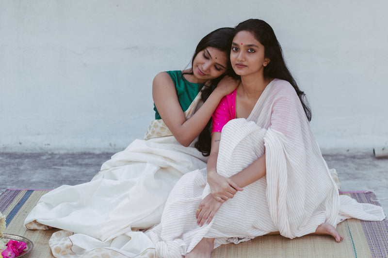 Soft muslin saree with golden striped pattern paired with a pink blouse and traditional accessories