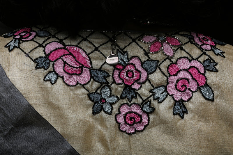Close-up back yoke of varsaaedit hand-embroidered saree blouse showing clustered pink roses on champagne-gold base.